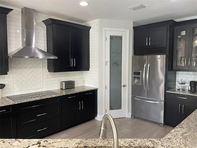 302 Coco Plum Ct, Oldsmar, FL 34677 - kitchen featuring stainless steel fridge, wall chimney range hood, black electric cooktop, dark cabinetry, and a textured ceiling