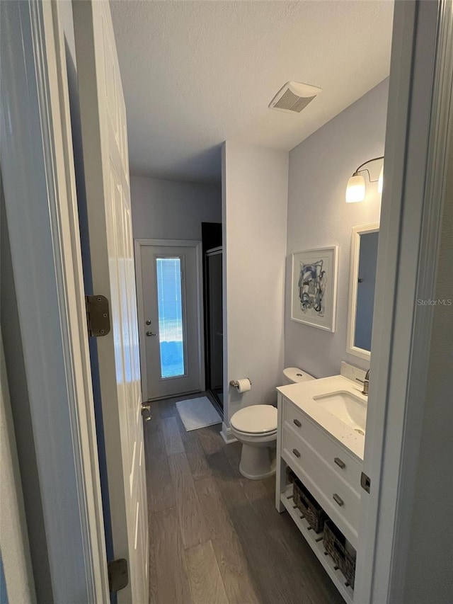 302 Coco Plum Ct, Oldsmar, FL 34677 - bathroom featuring wood finished floors, toilet, vanity, a stall shower, and a textured ceiling