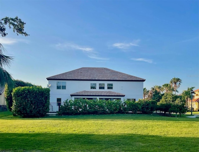 302 Coco Plum Ct, Oldsmar, FL 34677 - rear view of property featuring a lawn, a tiled roof, and stucco siding