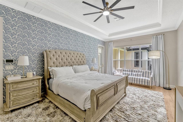 11721 Camden Park Dr, Windermere, FL 34786 - bedroom with wallpapered walls, crown molding, a tray ceiling, light wood-type flooring, and baseboards