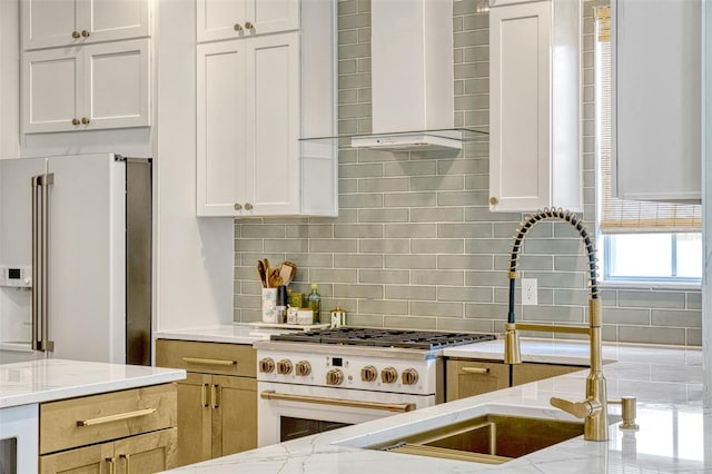 11721 Camden Park Dr, Windermere, FL 34786 - kitchen with wall chimney range hood, premium appliances, light stone countertops, decorative backsplash, and white cabinets