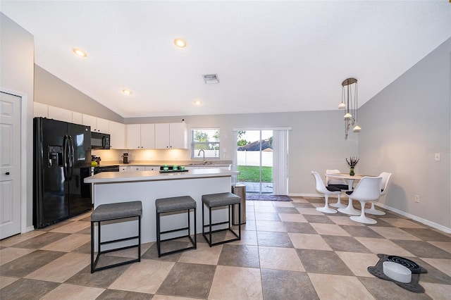 146 Hidden Pointe Ln, Groveland, FL 34736 - kitchen with black appliances, vaulted ceiling, light countertops, white cabinets, and a kitchen breakfast bar