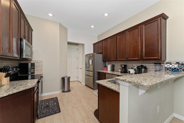 9348 Meadow Hunt Way, Winter Garden, FL 34787 - kitchen featuring stainless steel appliances, a peninsula, decorative backsplash, light stone countertops, and recessed lighting