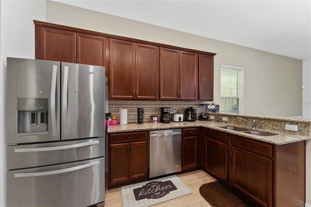 9348 Meadow Hunt Way, Winter Garden, FL 34787 - kitchen with appliances with stainless steel finishes, a sink, a peninsula, light stone countertops, and decorative backsplash