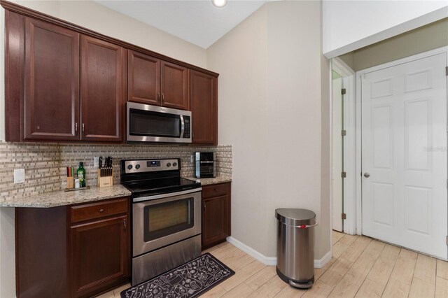 9348 Meadow Hunt Way, Winter Garden, FL 34787 - kitchen with stainless steel appliances, decorative backsplash, light wood-style flooring, baseboards, and light stone counters