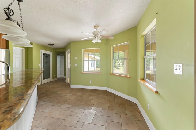 16017 Johns Lake Rd, Clermont, FL 34711 - spare room with baseboards, ceiling fan, a textured ceiling, and light stone finish flooring