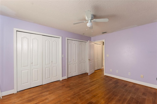 16017 Johns Lake Rd, Clermont, FL 34711 - unfurnished bedroom featuring multiple closets, wood finished floors, baseboards, a ceiling fan, and a textured ceiling