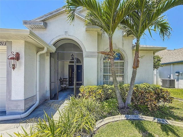1913 Blue River Rd, Holiday, FL 34691 - view of exterior entry featuring stucco siding and central air condition unit