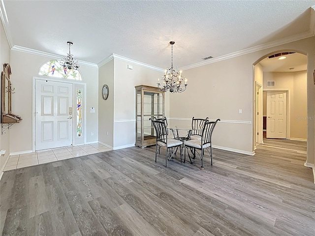 1913 Blue River Rd, Holiday, FL 34691 - dining space featuring a chandelier, arched walkways, wood finished floors, crown molding, and a textured ceiling