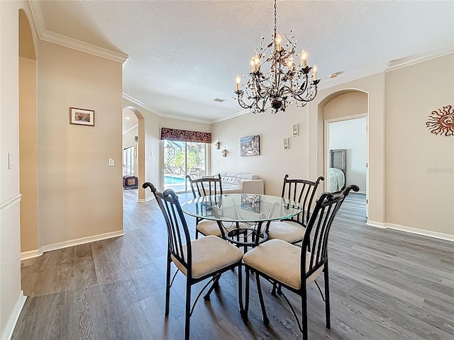 1913 Blue River Rd, Holiday, FL 34691 - dining space featuring arched walkways, wood finished floors, ornamental molding, a textured ceiling, and baseboards