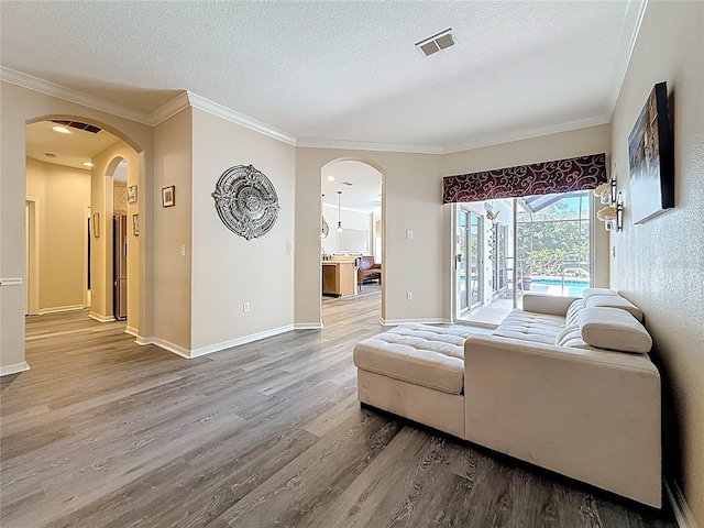 1913 Blue River Rd, Holiday, FL 34691 - living room with arched walkways, wood finished floors, crown molding, a textured ceiling, and baseboards
