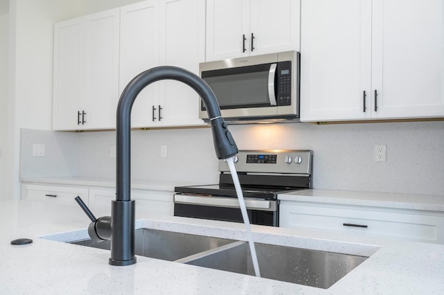 3211 SW 128th Street Rd, Ocala, FL 34473 - kitchen with stainless steel appliances, white cabinets, and light stone countertops