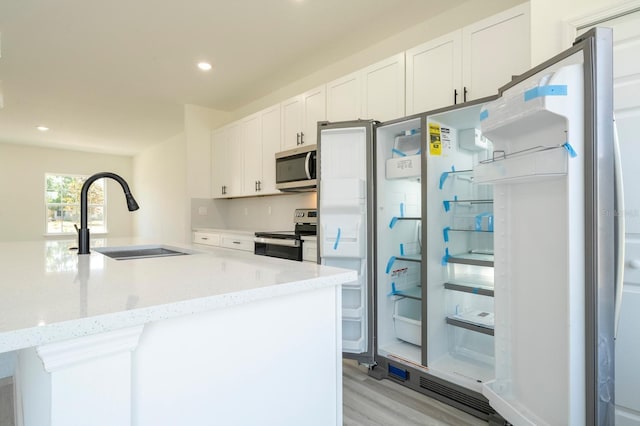 3211 SW 128th Street Rd, Ocala, FL 34473 - kitchen featuring appliances with stainless steel finishes, a sink, light wood-style flooring, white cabinetry, and light stone counters