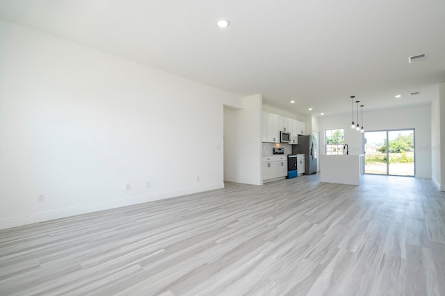 3211 SW 128th Street Rd, Ocala, FL 34473 - unfurnished living room with light wood finished floors, recessed lighting, baseboards, and a sink