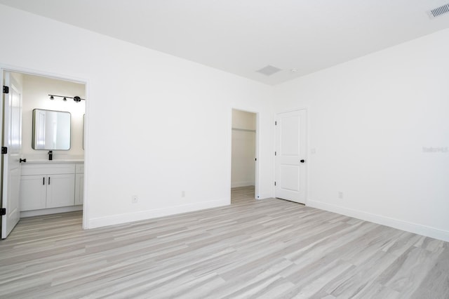 3211 SW 128th Street Rd, Ocala, FL 34473 - unfurnished bedroom featuring light wood-type flooring, connected bathroom, baseboards, and a walk in closet
