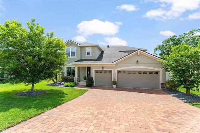 2401 Oxmoor Dr, Deland, FL 32724 - view of front of house featuring stucco siding, decorative driveway, an attached garage, a front yard, and roof with shingles