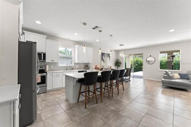 2401 Oxmoor Dr, Deland, FL 32724 - kitchen with appliances with stainless steel finishes, open floor plan, a kitchen breakfast bar, light countertops, and white cabinetry
