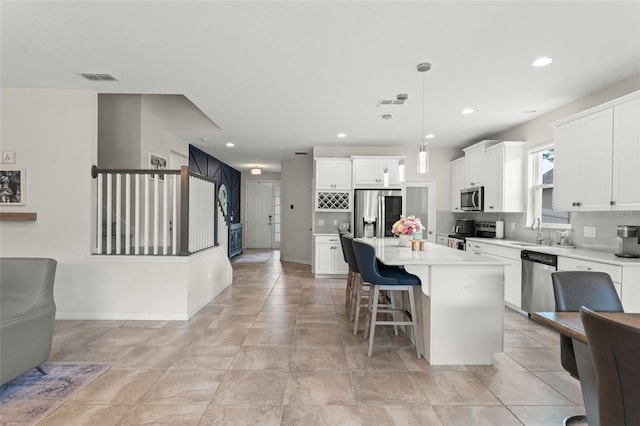 2401 Oxmoor Dr, Deland, FL 32724 - kitchen featuring appliances with stainless steel finishes, a sink, light countertops, a breakfast bar area, and white cabinetry