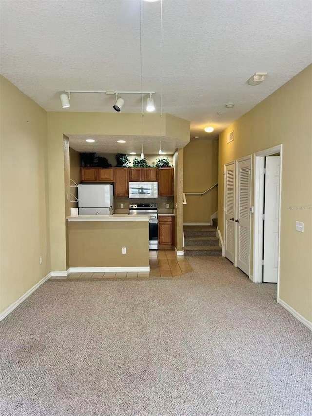 4010 Santa Maria Dr Unit 106, Kissimmee, FL 34741 - kitchen with white appliances, brown cabinetry, light carpet, baseboards, and a textured ceiling