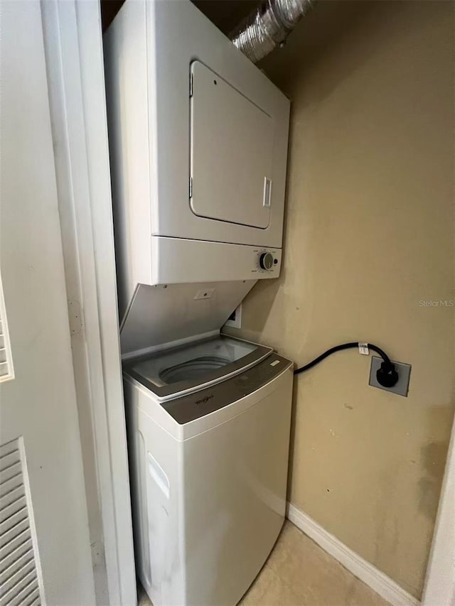4010 Santa Maria Dr Unit 106, Kissimmee, FL 34741 - laundry area with stacked washing machine and dryer, light tile patterned floors, and baseboards