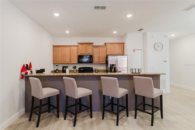 2923 Banana Palm Dr, Kissimmee, FL 34747 - kitchen with black microwave, stainless steel fridge, range, light wood-style floors, and baseboards