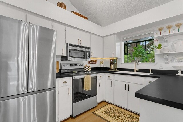 3501 Danby Ct, Orlando, FL 32812 - kitchen with stainless steel appliances, a sink, dark countertops, light wood-style flooring, and a textured ceiling