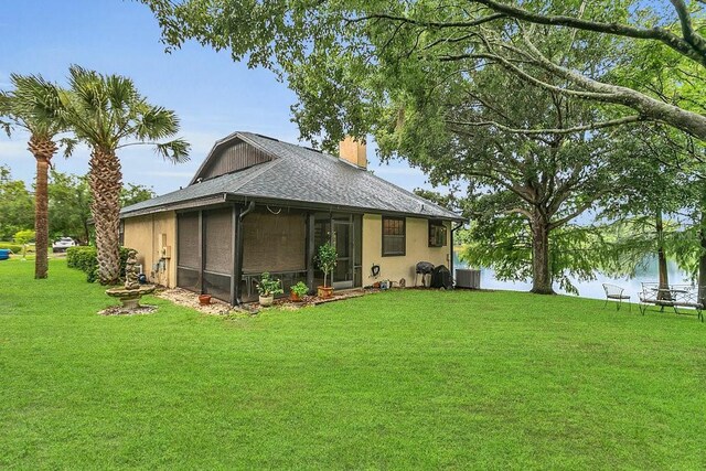 3501 Danby Ct, Orlando, FL 32812 - back of house featuring a lawn, a chimney, roof with shingles, central air condition unit, and stucco siding