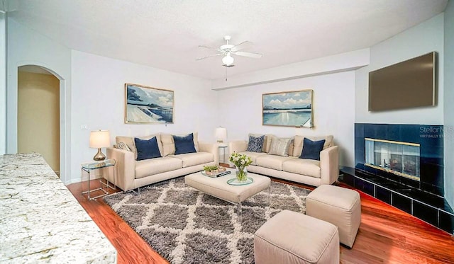 357 Fairway Pointe Cir, Orlando, FL 32828 - living area featuring a ceiling fan, wood finished floors, a tile fireplace, and arched walkways