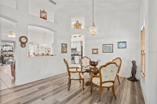 468 Alinole Loop, Lake Mary, FL 32746 - dining room featuring a ceiling fan, light wood-style flooring, arched walkways, a towering ceiling, and baseboards