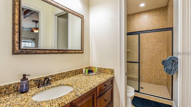 7411 Excitement Dr, Reunion, FL 34747 - bathroom featuring toilet, a shower stall, vanity, a textured wall, and recessed lighting
