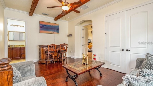 7411 Excitement Dr, Reunion, FL 34747 - living room featuring arched walkways, dark wood-type flooring, a ceiling fan, beam ceiling, and crown molding