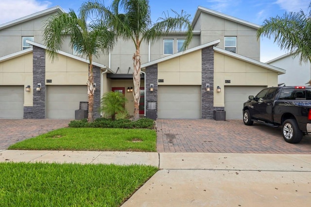 877 Ocean Course Ave, Davenport, FL 33896 - view of front of house with stone siding, driveway, an attached garage, and stucco siding