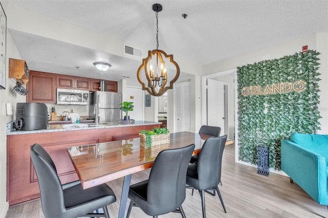 6337 Parc Corniche Dr Unit 2312, Orlando, FL 32821 - dining space featuring a chandelier, light wood-style floors, and a textured ceiling