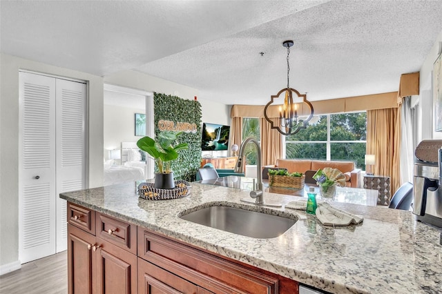 6337 Parc Corniche Dr Unit 2312, Orlando, FL 32821 - kitchen with a chandelier, light wood-style floors, light stone counters, pendant lighting, and plenty of natural light