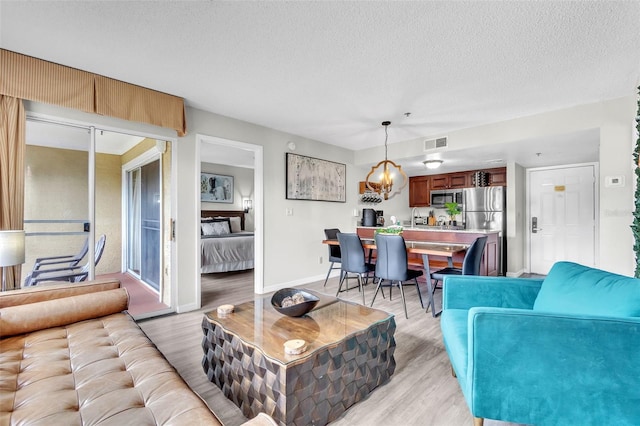 6337 Parc Corniche Dr Unit 2312, Orlando, FL 32821 - living room featuring light wood-style flooring, a textured ceiling, and a chandelier