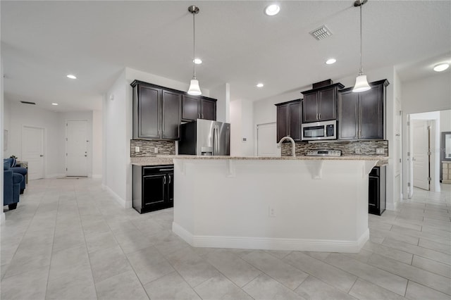 921 Costa Mesa Ln, Kissimmee, FL 34744 - kitchen with appliances with stainless steel finishes, tasteful backsplash, light stone counters, a breakfast bar area, and recessed lighting