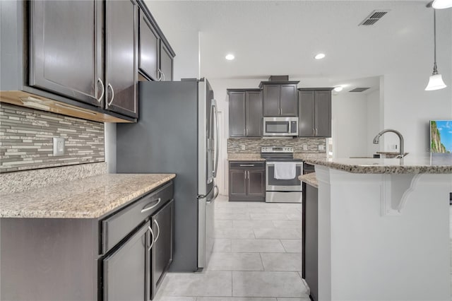 921 Costa Mesa Ln, Kissimmee, FL 34744 - kitchen featuring stainless steel appliances, decorative backsplash, light tile patterned floors, a kitchen breakfast bar, and recessed lighting