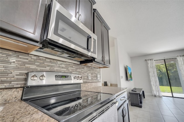 921 Costa Mesa Ln, Kissimmee, FL 34744 - kitchen with stainless steel appliances, backsplash, light tile patterned floors, light stone countertops, and baseboards