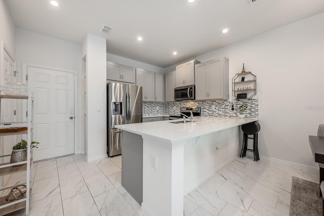 10221 Highline Crest St, Orlando, FL 32832 - kitchen featuring stainless steel appliances, light marble finish floors, a peninsula, gray cabinetry, and a kitchen bar