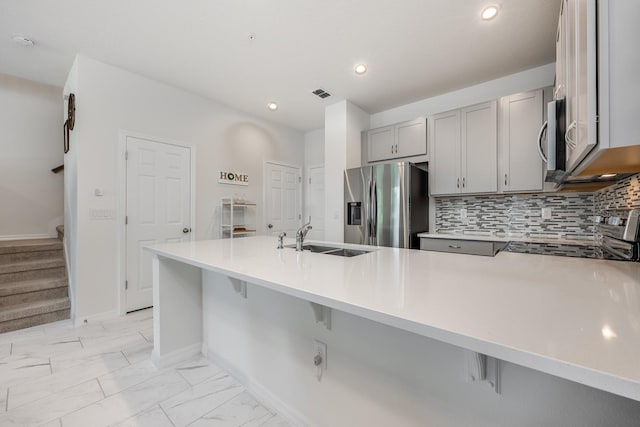 10221 Highline Crest St, Orlando, FL 32832 - kitchen with stainless steel appliances, a sink, gray cabinets, a peninsula, and a breakfast bar