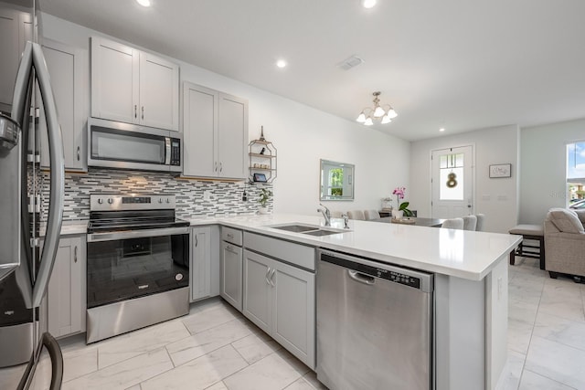 10221 Highline Crest St, Orlando, FL 32832 - kitchen featuring stainless steel appliances, light marble finish floors, open floor plan, gray cabinets, and a peninsula