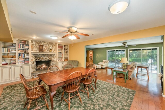 6321 Quarterhorse Cir, Cocoa, FL 32926 - dining space featuring ceiling fan, a stone fireplace, light wood-style floors, and built in features