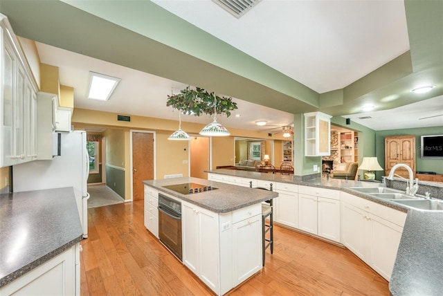 6321 Quarterhorse Cir, Cocoa, FL 32926 - kitchen with black appliances, dark countertops, light wood-style floors, white cabinetry, and a breakfast bar
