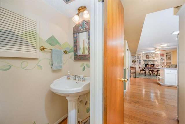 6321 Quarterhorse Cir, Cocoa, FL 32926 - bathroom featuring wood finished floors, a stone fireplace, built in shelves, a ceiling fan, and a sink
