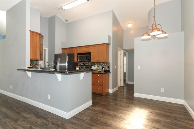 5165 Mystic Point Ct, Orlando, FL 32812 - kitchen with stainless steel appliances, dark countertops, a peninsula, brown cabinetry, and a breakfast bar area