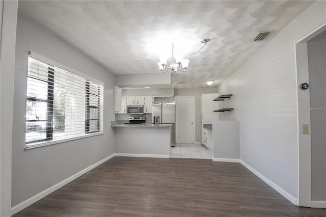 1668 Fort Smith Blvd, Deltona, FL 32725 - kitchen with stainless steel appliances, a chandelier, white cabinetry, a peninsula, and wood finished floors