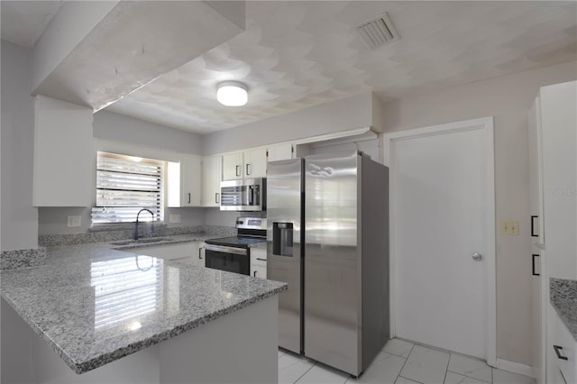 1668 Fort Smith Blvd, Deltona, FL 32725 - kitchen with appliances with stainless steel finishes, a peninsula, white cabinets, light stone counters, and a sink