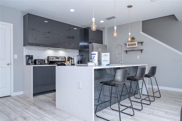 4414 Le Reve Ct, Kissimmee, FL 34746 - kitchen featuring stainless steel appliances, modern cabinets, a kitchen bar, light wood-style floors, and recessed lighting
