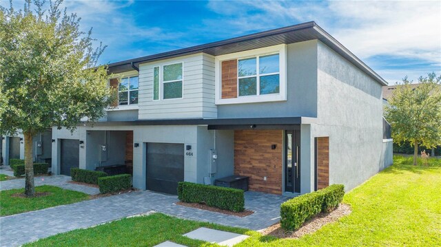 4414 Le Reve Ct, Kissimmee, FL 34746 - view of front facade with an attached garage, stucco siding, a front lawn, and decorative driveway