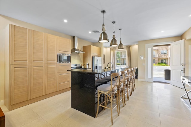 3149 Brasilia Ave, Kissimmee, FL 34747 - kitchen with appliances with stainless steel finishes, wall chimney exhaust hood, light brown cabinetry, a kitchen island with sink, and light tile patterned floors